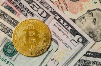 Close-up of a gold Bitcoin coin placed on various US dollar bills, illustrating digital currency concepts.