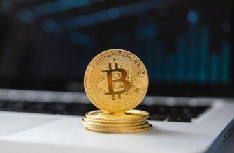 A shiny gold Bitcoin coin on laptop keyboard, symbolizing digital currency and blockchain technology.