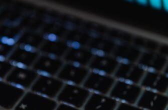 Gold Bitcoin coin on a laptop keyboard with trading chart display.
