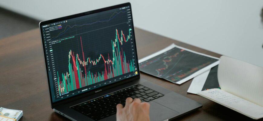 A person analyzing stock market data on a laptop with charts and graphs visible.