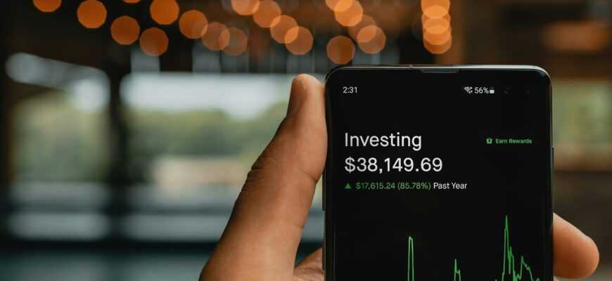 a person holding up a cell phone with a stock chart on it